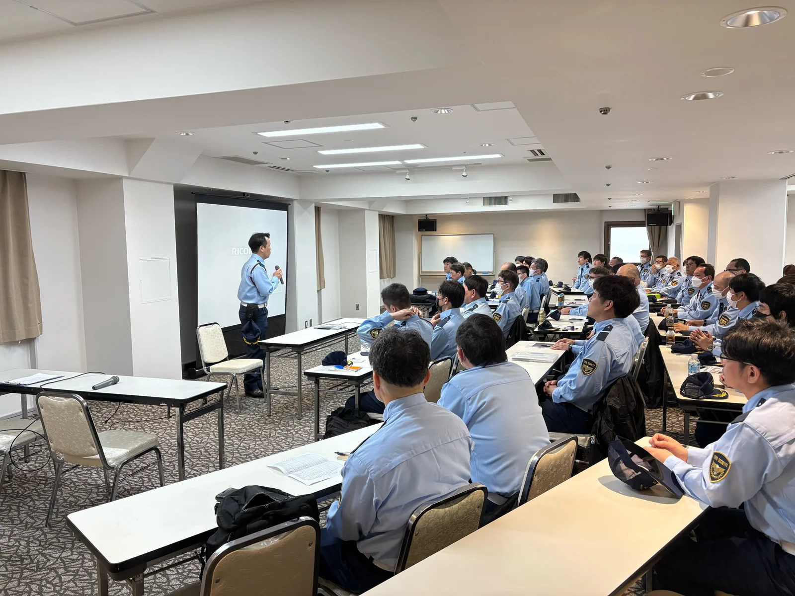 講師の説明を聞く制服姿の警備士たち